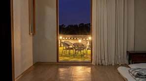 A room with a large sliding glass door leading to an outdoor seating area with chairs and a table, and a bed with a patterned blanket. - Gyeongju Hanokhotel Chunchugwan (Gyeongju)