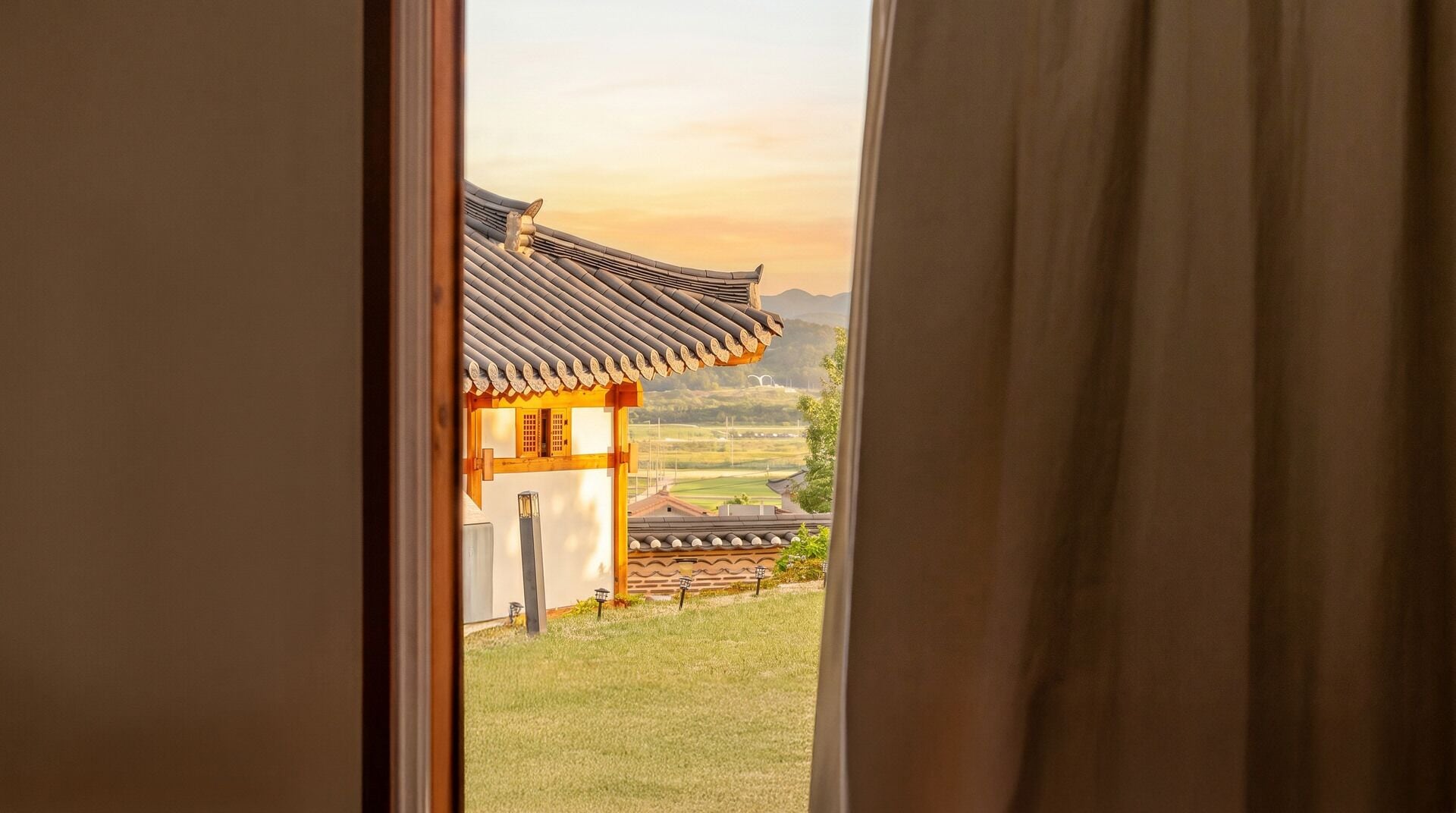 A traditional building with a tiled roof and wooden structure, viewed through an open window.