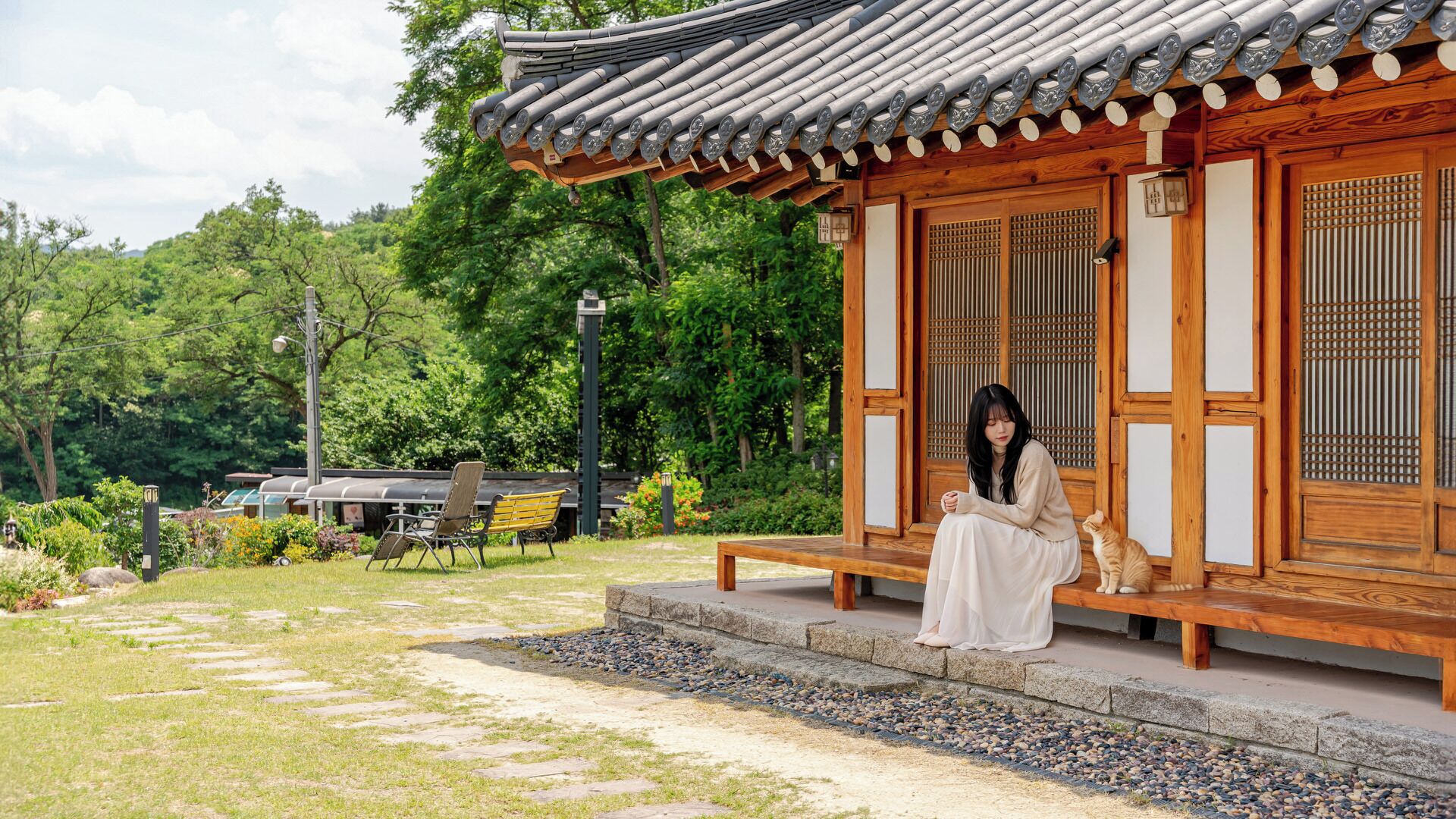 A traditional wooden building with a tiled roof, a stone pathway, and a bench.
