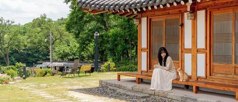 A traditional wooden building with a tiled roof, a stone pathway, and a bench.