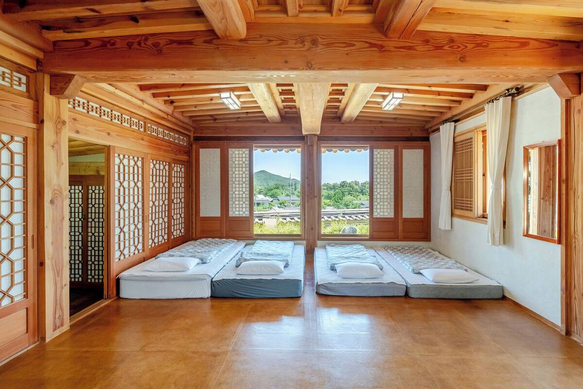 A traditional Japanese-style room with tatami flooring, sliding doors, and a view of greenery outside.