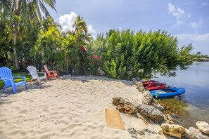 A beach with chairs, kayaks, and a palm tree. - Key West Beach House with heated pool, tiki, and dock.♿︎ (Key West)