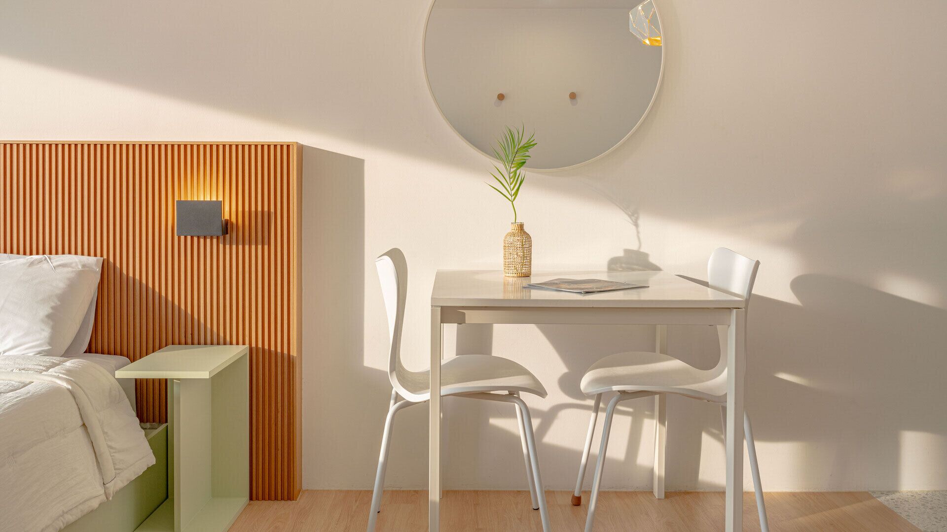 A modern bedroom with a bed, bedside table, and a small table with chairs.