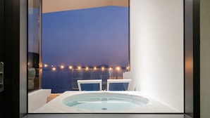 A modern bathroom with a large bathtub, a glass shower enclosure, and a view of the sea at dusk. - Namhae Pumda Pool Villa Pension (Namhae)