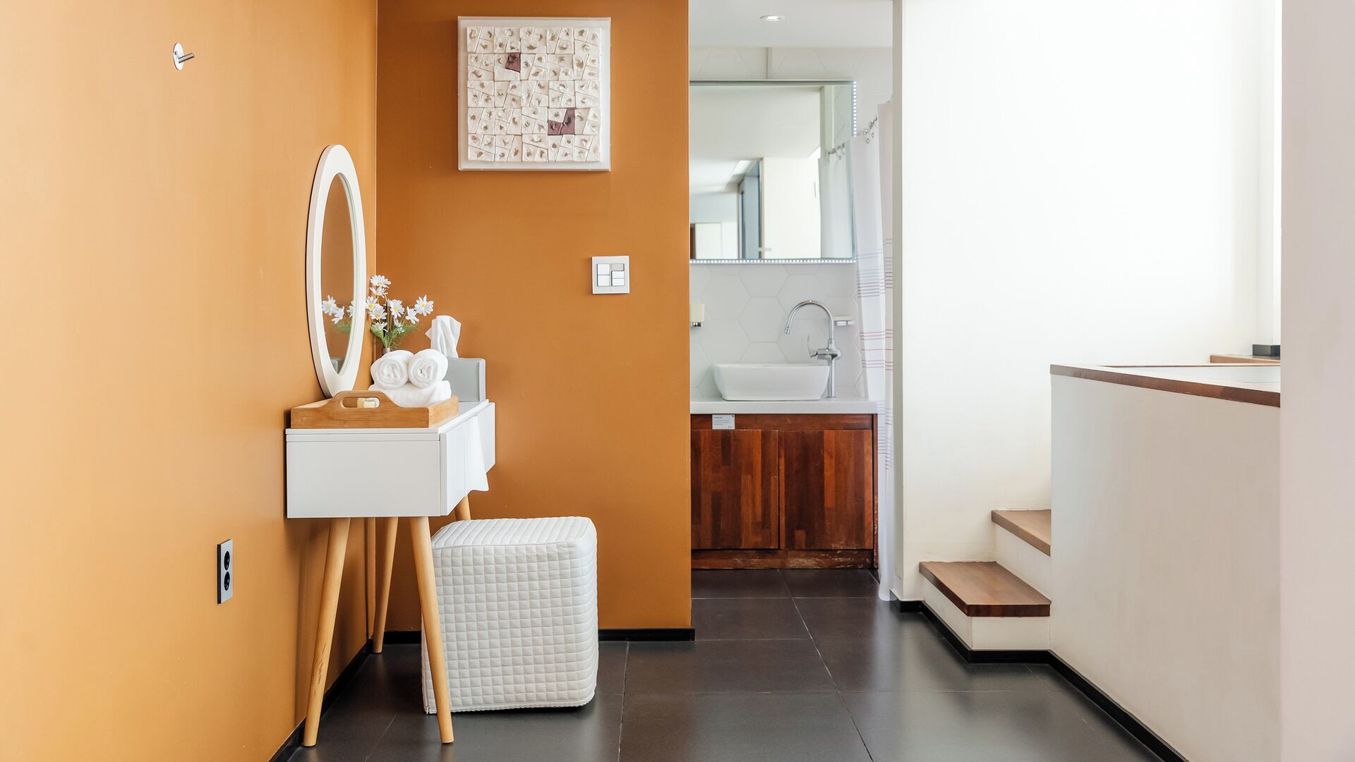 Un baño moderno con tocador, espejo y un ventanal grande.