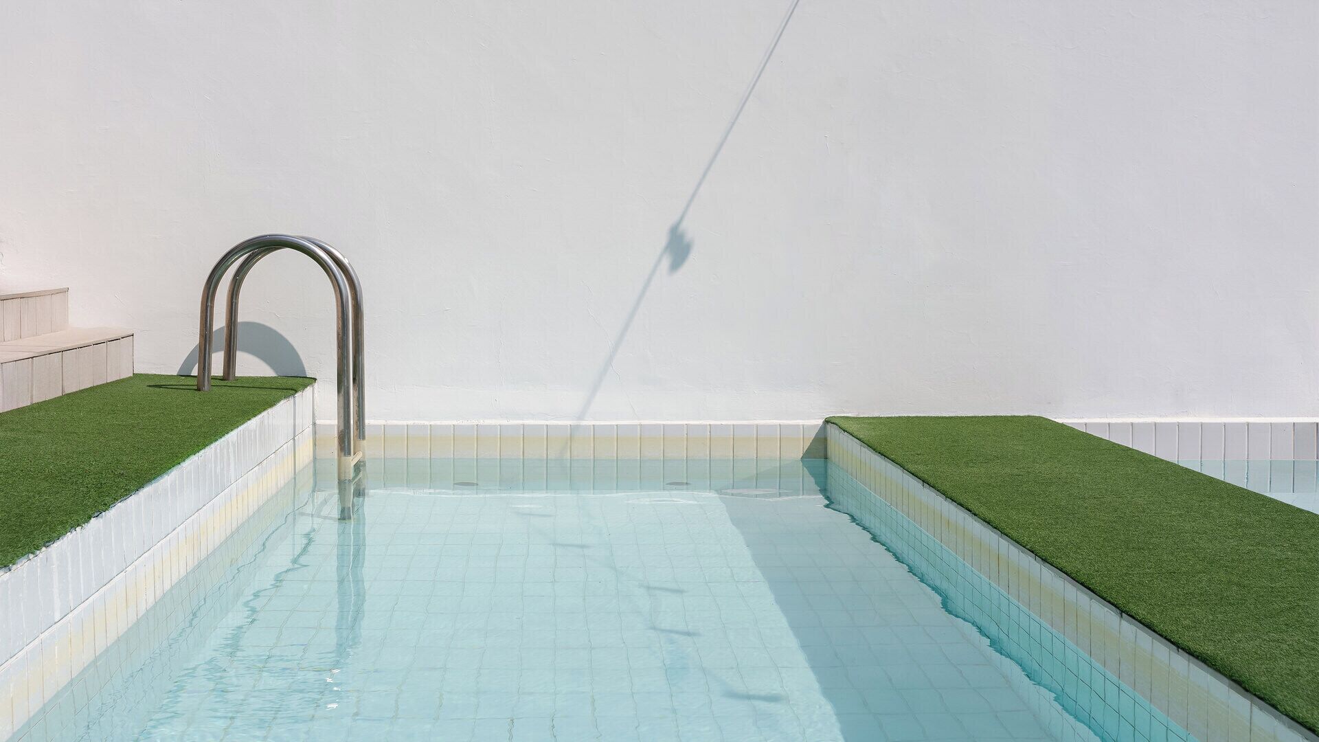 Una piscina con una entrada en arco de metal y paredes con azulejos.