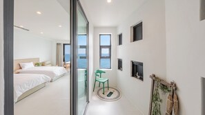 A modern hotel room with a balcony, a bed, a chair, and a fireplace.