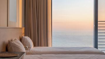 Ein Hotelzimmer mit Bett, Nachttisch und Meerblick.