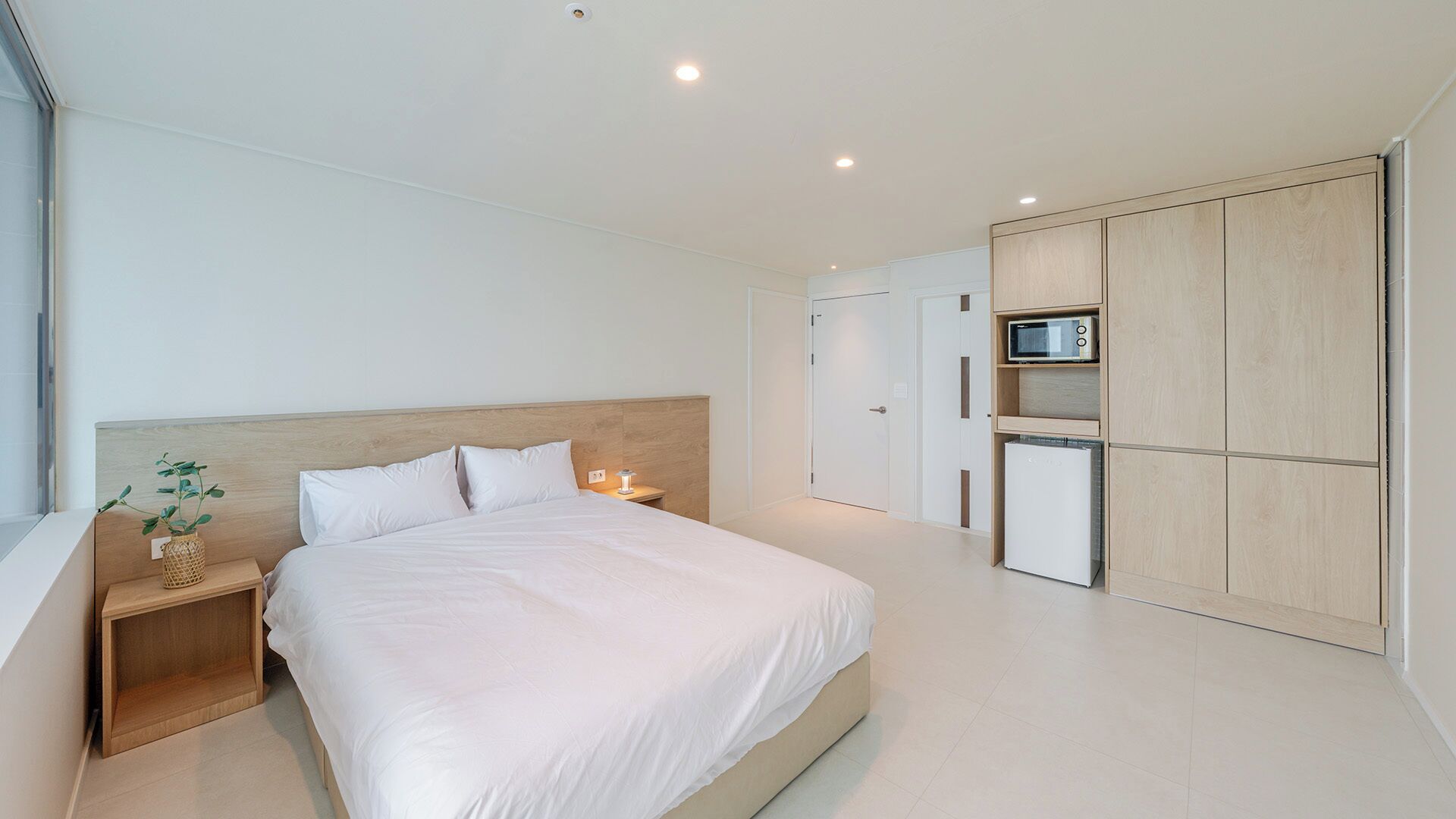 Ein modernes Schlafzimmer mit Bett, Nachttisch und einer kleinen Pflanze.