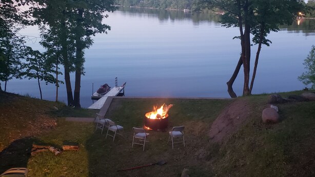 Un espace aménagé au bord du lac, avec un foyer, des chaises et un quai.