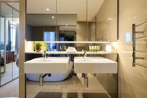Une salle de bain moderne avec deux lavabos, un grand miroir et un porte-serviettes.