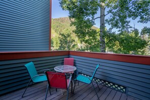 Enjoy a peaceful forest view from this balcony with a table and chair.