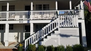 A two-story building with a white exterior, a balcony with a white railing, and an American flag. - The Prickly Pear Cottage in Wrightsville Beach (Wrightsville Beach)
