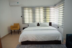A bedroom with a bed, a chair, and a window with blinds. - Cosy Rooms Away in a Stunning House (Koforidua)
