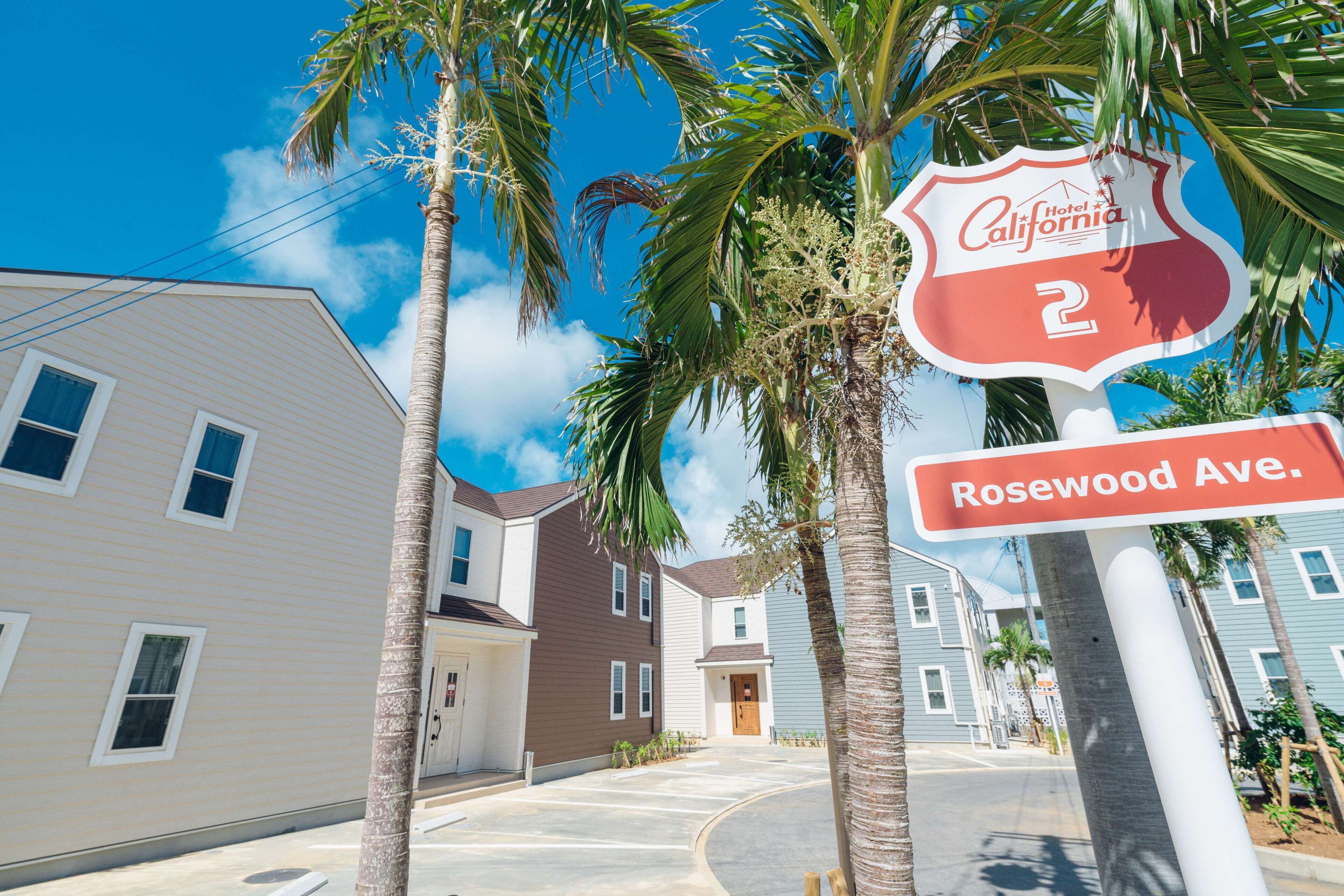 A residential street with houses, palm trees, and a hotel sign.