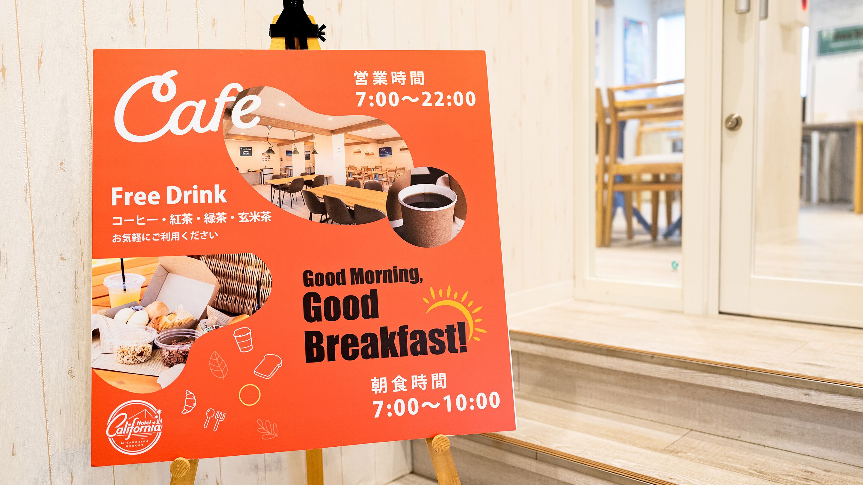 A cafe sign with operating hours and free drink offerings.