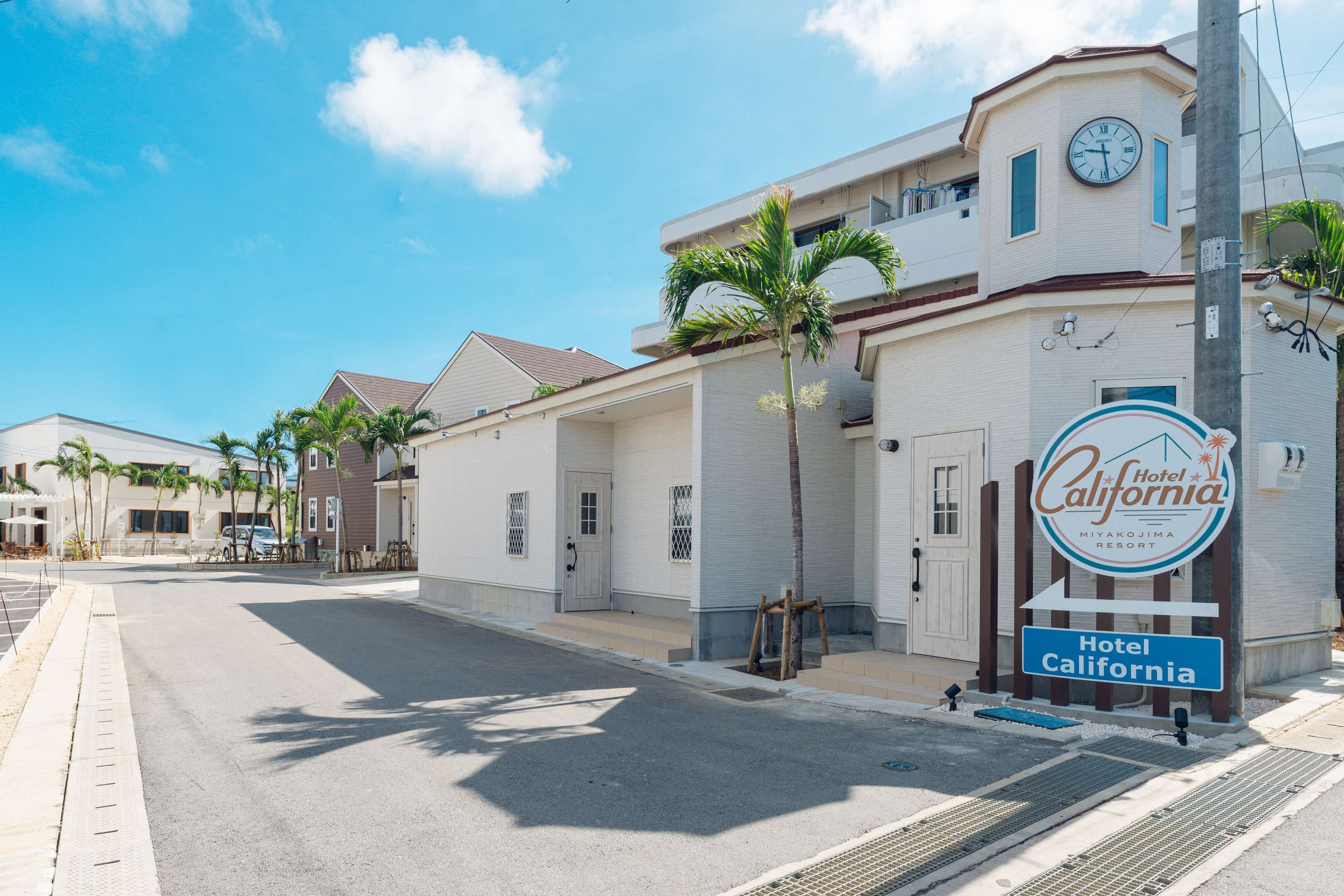 A hotel named Hotel California with a clock and palm trees in front.