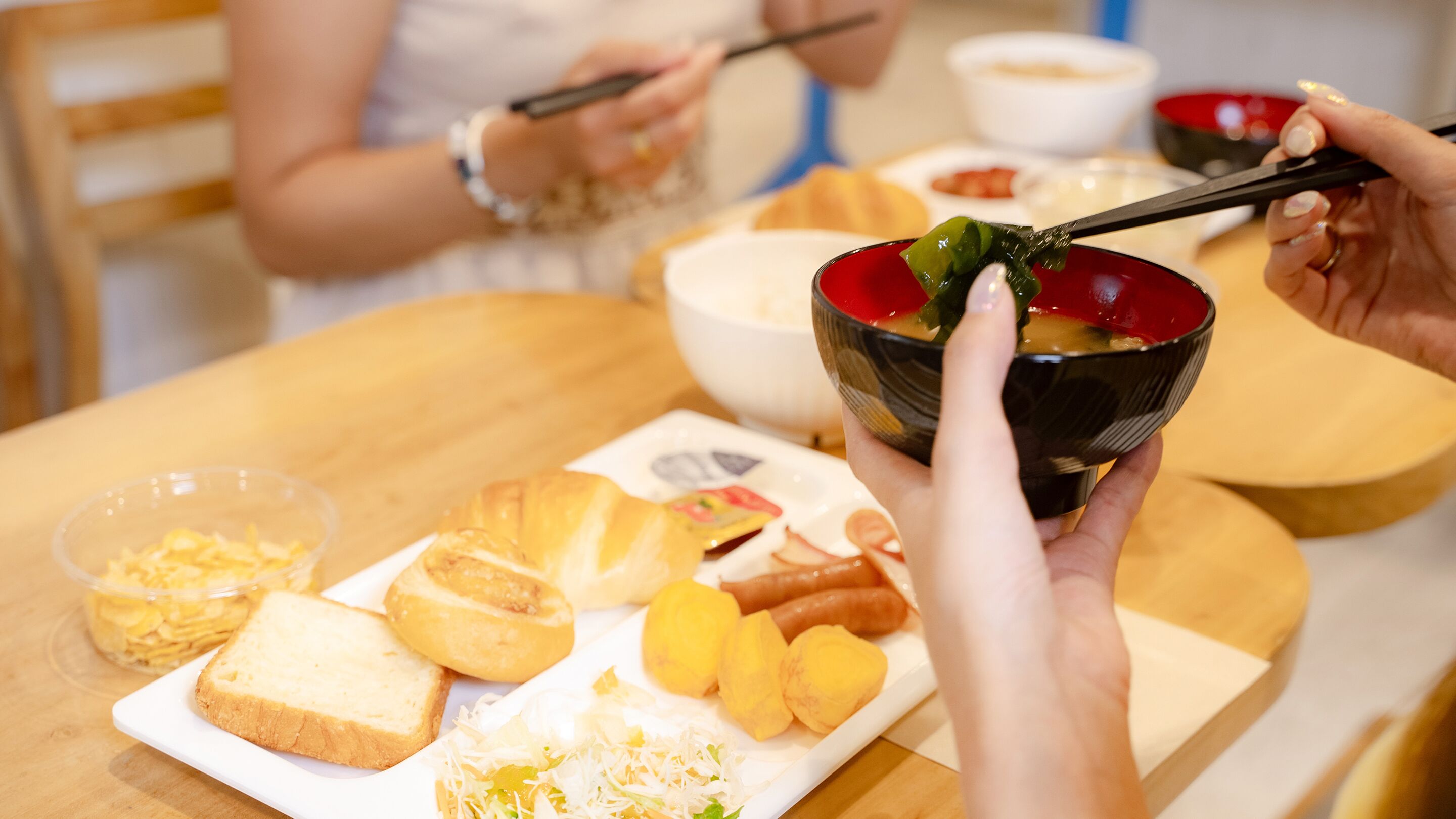 Ein Esstisch mit Speisen, darunter Brot, eine Schüssel Suppe und ein Teller mit verschiedenen Snacks.