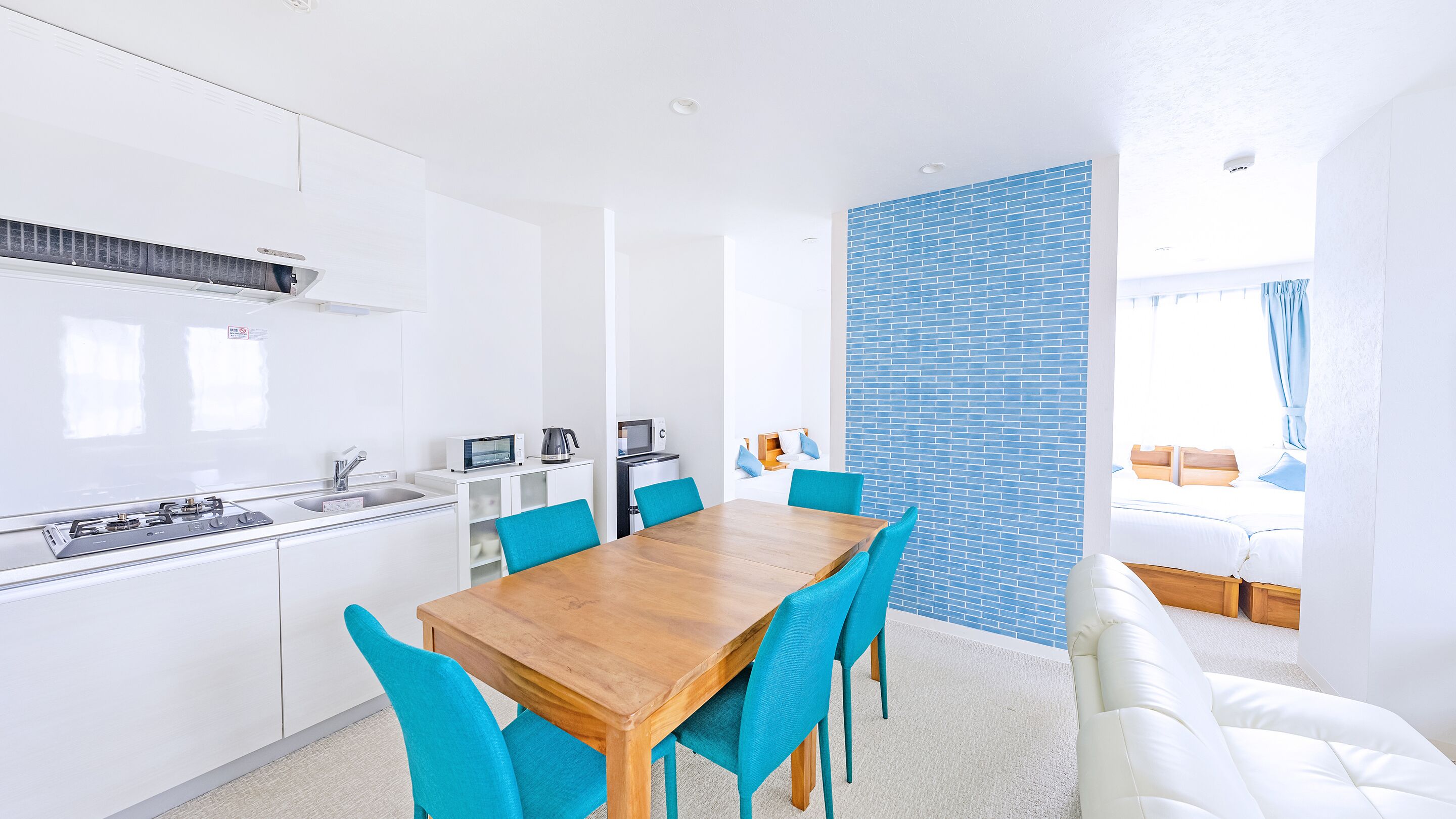 Una cocina moderna con armarios blancos, una mesa de comedor de madera y sillas azules.