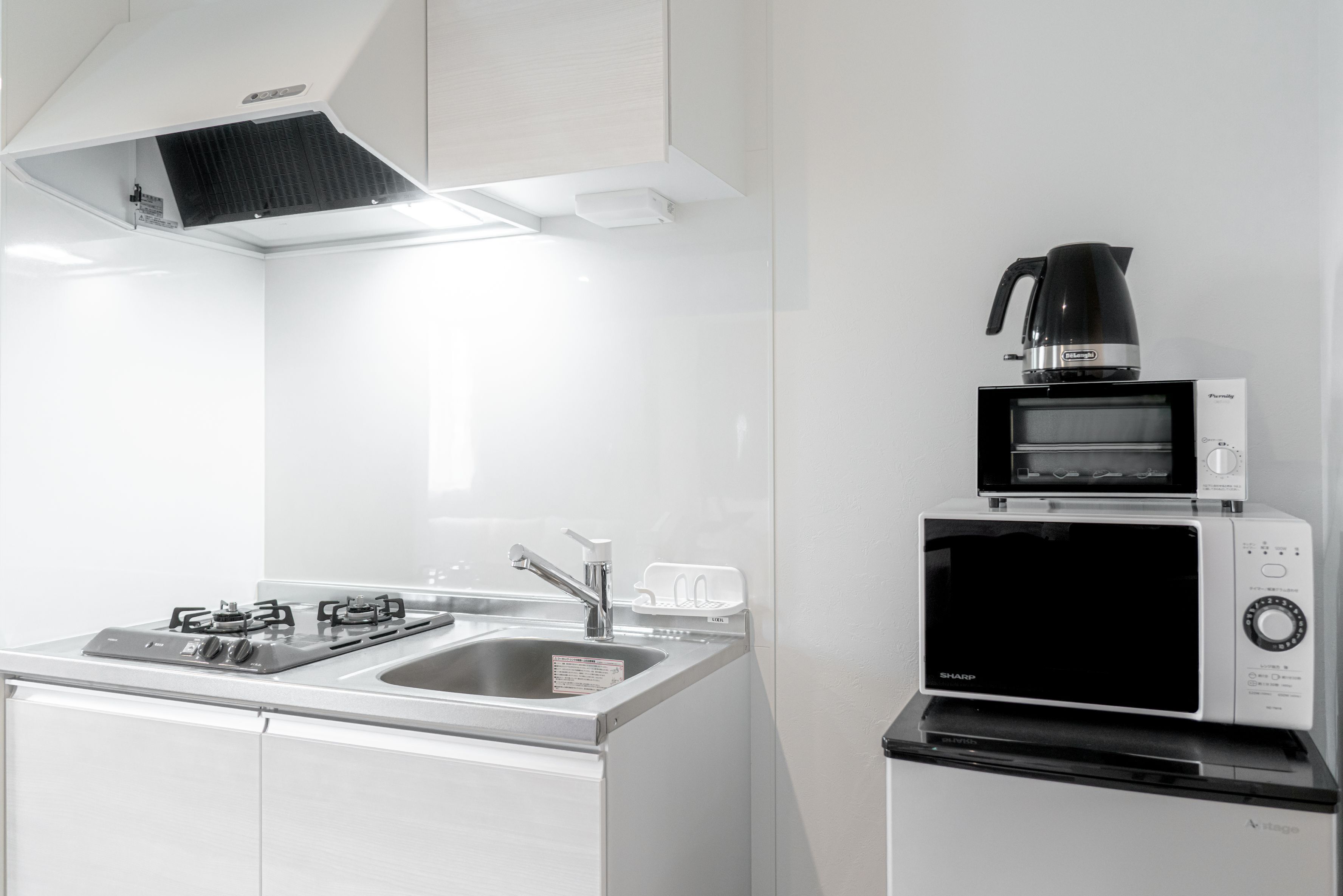 Una cocina moderna con estufa a gas, lavamanos y cafetera sobre la encimera.