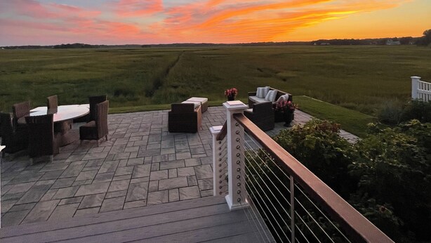 An outdoor deck with a view of a sunset over a grassy field. - New England, Coastal Beachside (DUXBURY)