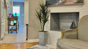 A living room with a fireplace, a large painting, a potted plant, and a sofa. - New England, Coastal Beachside (DUXBURY)