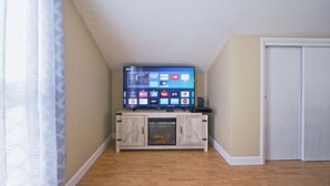 A room with a television on a wooden cabinet, a door, and a window with curtains. - Entire apartment, close to Hershey  (Palmyra)