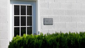 A white window with a grid pattern, a small sign on the wall, and a hedge in front. - Entire apartment, close to Hershey  (Palmyra)