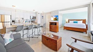 Une chambre d’hôtel moderne équipée d’une cuisine, d’un coin repas, d’un canapé, d’une table basse en bois et d’un lit.
