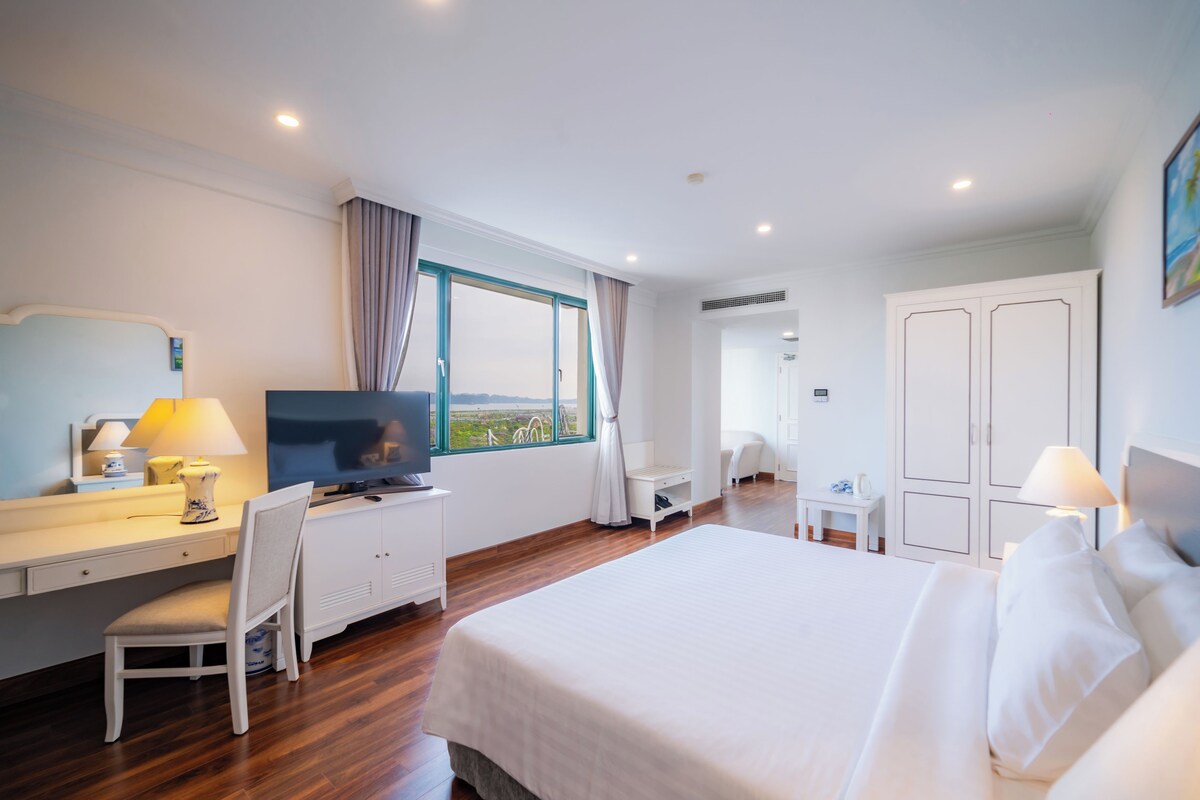A hotel room with a bed, desk, chair, TV, and a window with curtains.