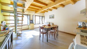 Une cuisine spacieuse avec des poutres en bois, un coin repas avec des chaises et un escalier en colimaçon.
