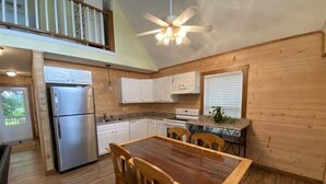 A spacious kitchen with wooden cabinets, a stainless steel refrigerator, and a dining table with chairs. - Riverfront Retreat & Fisherman's Gold, on TN River (Savannah)