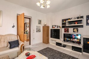 Uma sala de estar com sofá, televisão, estantes e uma porta.