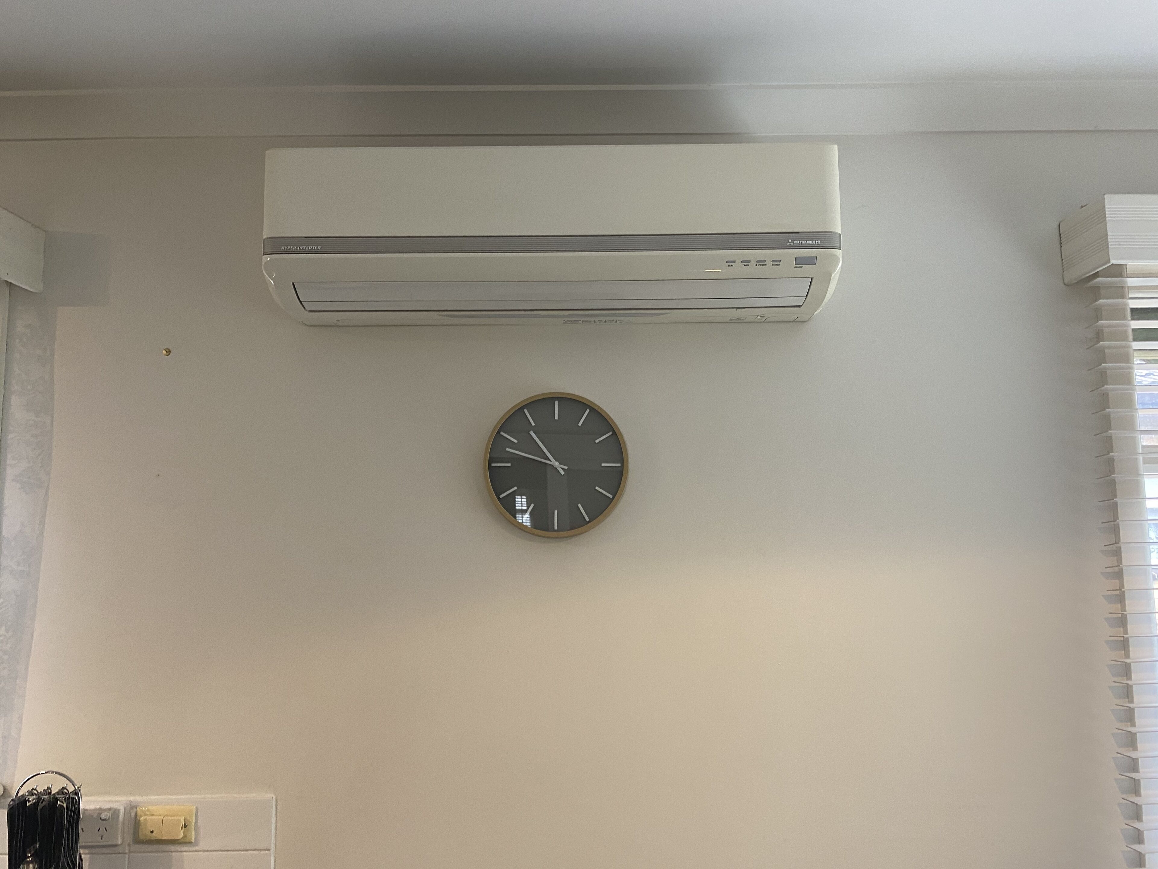 Una habitación con aire acondicionado de pared y un reloj redondo en la pared.