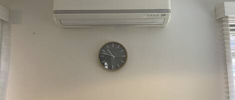 Una habitación con aire acondicionado de pared y un reloj redondo en la pared.