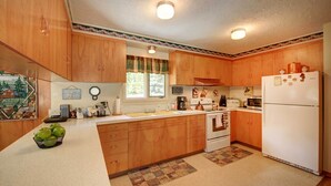 Eine Küche mit Holzschränken, einem Kühlschrank, einem Herd und einem Spülbecken.