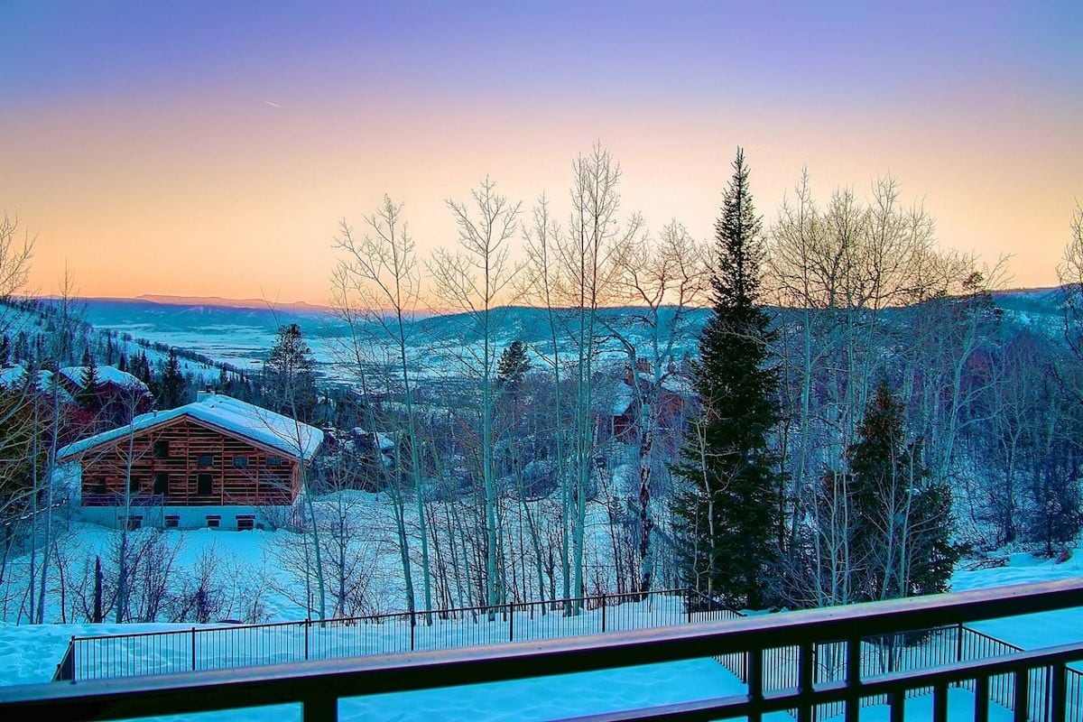 A wooden cabin with a snow-covered landscape and a clear sky.