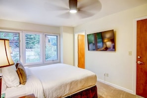 A bedroom with a bed, a window, a painting, and a door. - Steps to Trails-Pool-Hot Tub-W/D in Unit-Grill (Steamboat Springs)