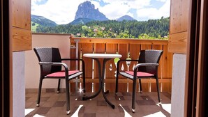 Un balcone con due sedie in vimini e un tavolino, con vista su un paesaggio montuoso.