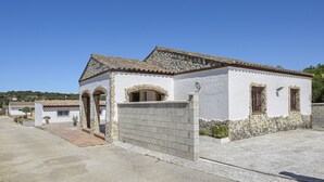 Um edifício branco com fachada de pedra, arcadas e telhado em tijolos.