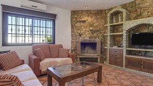 Uma sala de estar com lareira de pedra, televisão e sofá.