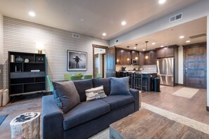 A modern living room with a dark-colored sofa, a coffee table, and a wooden floor. - Blackstone Lofts 2B (Park City)