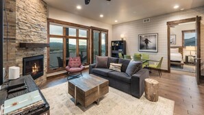 Ein geräumiges Wohnzimmer mit Kamin, großem Fenster mit Bergblick, modernem Deckenventilator und einer gemütlichen Sitzecke.
