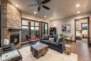 A spacious living room with a fireplace, a large window offering a view, a ceiling fan, and a cozy seating area. - Blackstone Lofts 2B (Park City)