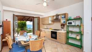 Una cucina con zona pranzo, una ventola a soffitto e vista attraverso una porta aperta.