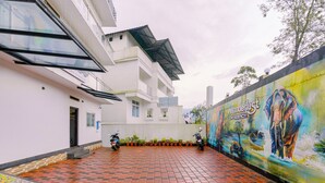 Ein Wohngebäude mit einem mit Fliesen bepflasterten Innenhof, einem Elefanten-Mural und zwei abgestellten Motorrädern.