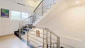 Eine moderne Treppe mit Glastrennläufern und Blick ins Freie durch ein Fenster.