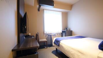 A hotel room with a bed, desk, chair, and a television.