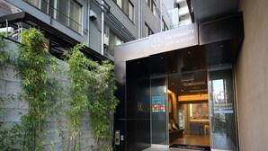 The exterior of The Dynasty Hotel & Resort with a modern design, featuring a glass entrance and a signboard. - Dynasty Hotel & Resort Osaka (Osaka)