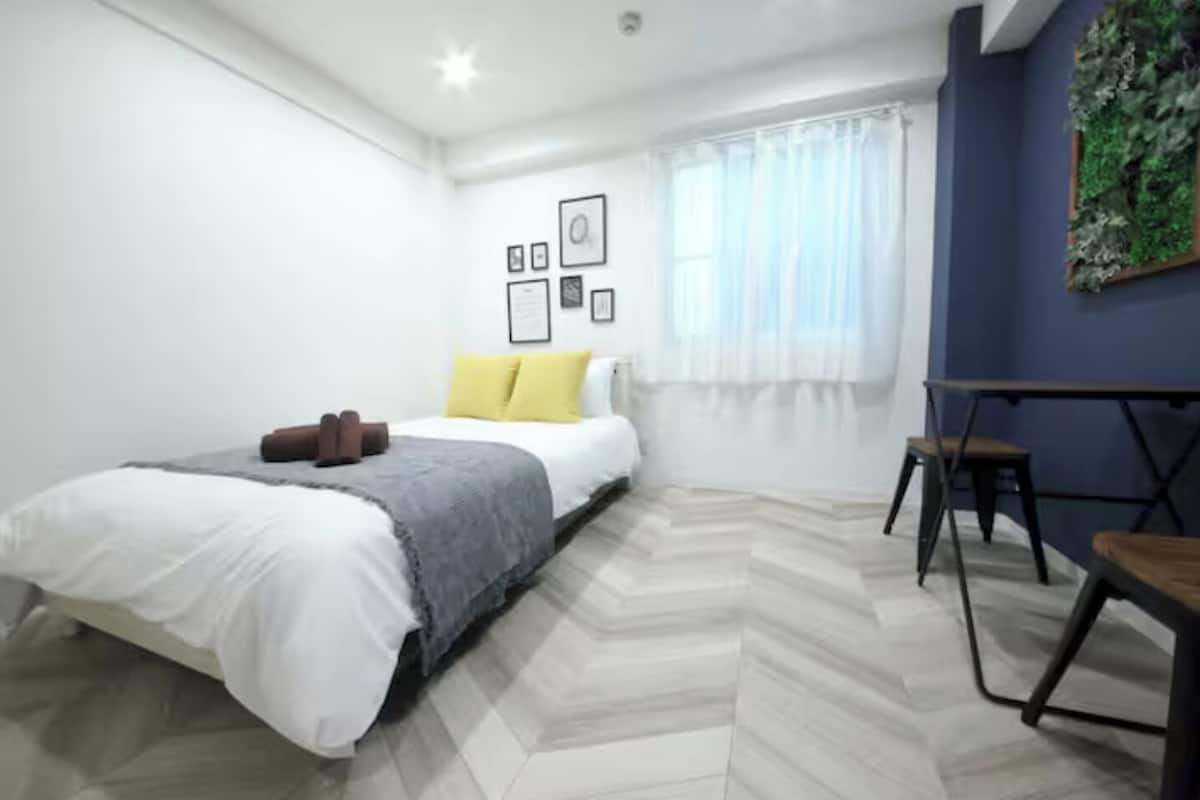 A bedroom with a bed, a desk, and a chair.